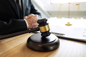 Obraz na płótnie Canvas Legal law, advice and justice concept, male lawyer or notary working on a documents and report of the important case and wooden gavel, balance on table in courtroom