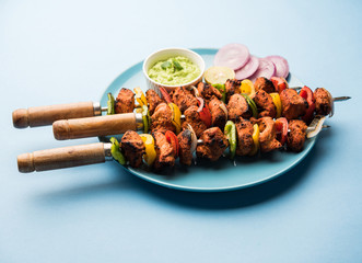 Chicken tikka /skew Kebab. Traditional Indian dish cooked on charcoal and flame, seasoned & colourfully garnished. served with green chutney and salad. selective focus