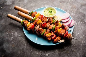 Chicken tikka /skew Kebab. Traditional Indian dish cooked on charcoal and flame, seasoned & colourfully garnished. served with green chutney and salad. selective focus