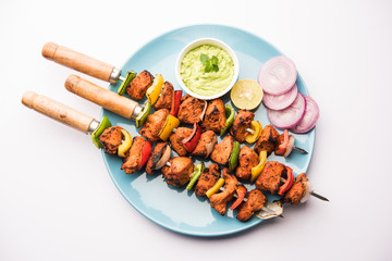 Chicken tikka /skew Kebab. Traditional Indian dish cooked on charcoal and flame, seasoned & colourfully garnished. served with green chutney and salad. selective focus
