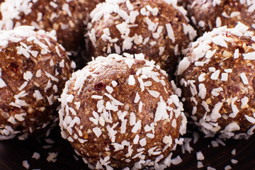 Obraz na płótnie Canvas Healthy homemade sweet energy balls of dried fruits and nuts in coconut chips. As part of dates, oatmeal, coconut chips, peanuts, lemon peel. Proper nutrition for a healthy lifestyle. Close-up.