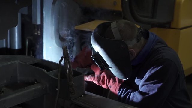 The welder does the work. Man at work. Welding work. Welder costume. Working. Welding mask. Welding electrodes. Ventilation in production. Harmful work. Welding equipment.