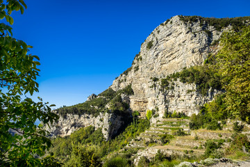 Rocky cliffs on Amalfi coast in Italy, covered green vegetation.