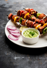 Fototapeta na wymiar Indian chicken tikka kebabs, marinated in spices and yogurt and roasted in tandoor. served with green chutney and onion. selective focus