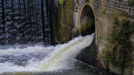 Water coming out of river canal lake overflow pipe showing white water rapids