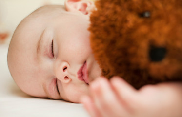 cute little baby sleeping in a sweet sleep hugging a bear