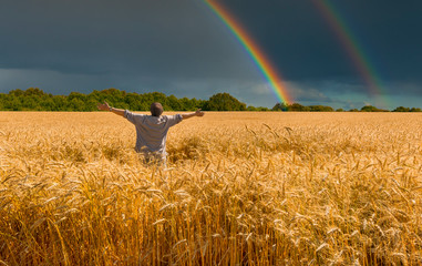 Field with ripening wheat, happy farmer and approaching thunderstorm