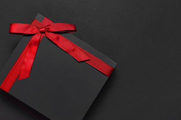 Black gift box with red ribbon on dark background top view flat lay. Holiday concept, birthday gift, father's day, Valentine's Day, new year or Christmas presents Xmas. Congratulations background - Powered by Adobe