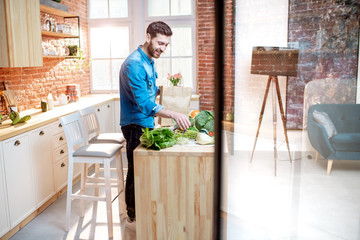 Man cooking healthy food standing on the kitchen of the beautiful loft apartment