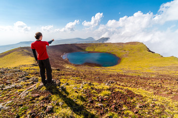 Man on a summit of Azhdahak volcano watching crater lake, Geghama mountains, Armenia