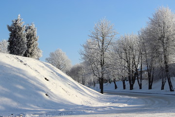 Winter road trip and beautiful icy trees on snowy hill on blue sky background on sunny day - winter lanscape