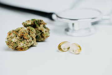 Medizinische Cannabis-Öl-Kapseln mit Cannabis Knospen und Stethoskop im Hintergrund