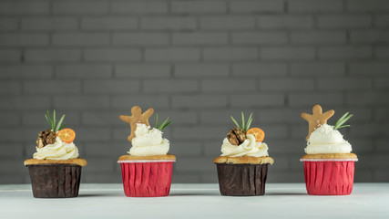 Four Christmas cupcakes with kumquat, walnuts and ginger cookies on the table