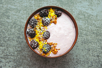 Fototapeta na wymiar Colorful healthy breakfast bowl with pink yogurt and blackberries.