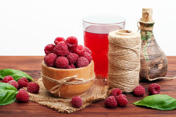Raspberries in a wooden plate on a brown wooden board. Delicious fresh forest berries. Nearby berry fruit drink. Shallow depth of field, blurred background