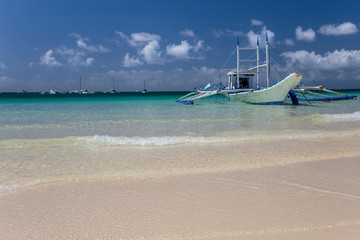 Traditional Philippine double-outrigger boat,  known as bangka, banca and paraw, at a pristine white sand beach
