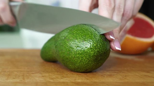 Woman cutting avocado in the kitchen.