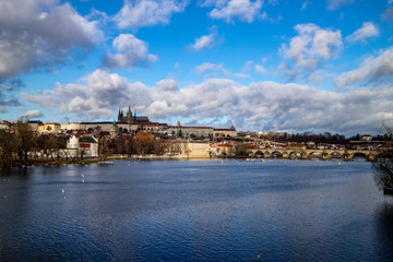 Prague, Czech Republic, Europe, panorama overlooking the historic buildings of Prague Castle, Charles Bridge and the Vltava River in front of interesting blue sky with clouds