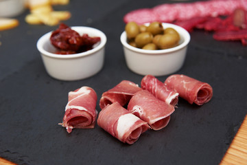 charcuterie meat assortment and green olives on stone slate