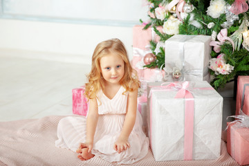 Little beautiful girl with Christmas gifts next to the Christmas tree
