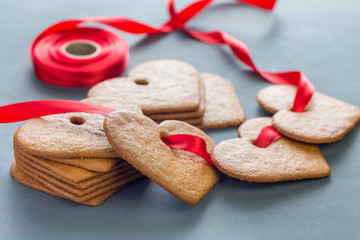 Holiday sweets. Swedish christmas gingerbread cookies pepparkakor, decorated with a red ribbon, on a dark gray background, horizontal