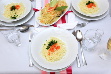 Makaron, marchewka i pietruszka na białym talerzu na stole weselnym.