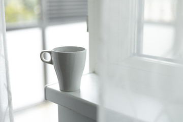 A cup of coffee on the windowsill. Big window. Scandinavian style