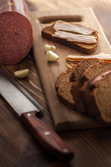 bacon and sausage with black bread and garlic on a wooden table