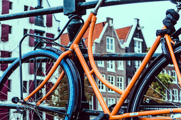 Fototapeta na wymiar oranges Fahrrad auf Brücke vor Häuserfassade
