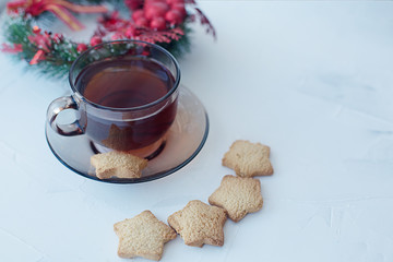 Cup of tea with cookies on a light textural background and a Christmas wreath on the plan