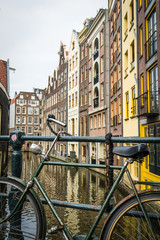 Fototapeta na wymiar Fahrrad auf Brücke mit Gracht und Häuserfassade in Amsterdam