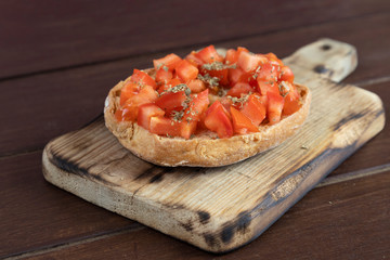 Friselle or Freselle Italian appetizer on wooden board with tomatoes, tuna, garlic, oregano, salt, and peppercorns. Italian food. A quick and easy snack for party time