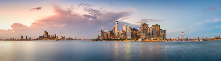 New York City financial district skyline panorama from across the harbor at dusk.