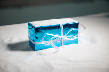 Christmas gift or New Year with blue ribbon on rustic wood table on bokeh background. Handmade gift concept.