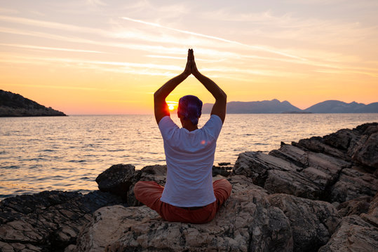 Male traveler practice yoga on the coastline