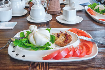 Burato cheese and lettuce for the correction of the weight of the leaves of Lollo Rosso lettuce and tomatoes. Restaurant food. The concept of healthy eating.