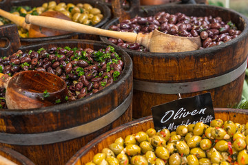 Viele Sorten eingelegter, schwarzer und grüner Oliven mit Petersilie, die auf dem Markt zum Verkauf angeboten werden