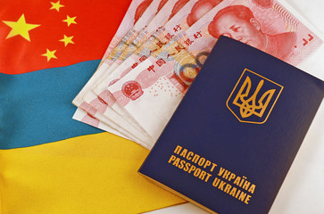Ukrainian passport and yuans on background of flags Ukraine and China