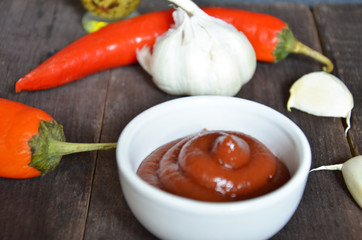 red hot sweet chilli sauce,ketchup over old wooden background with ingredients garlic ginger