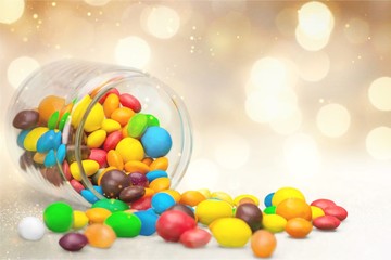 Colorful candies sweets falling out of a glass jar, composition