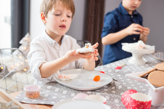 Brothers making "melted snowman" cookies with marshmellows and royal icing. Candid, lifetyle image with shallow depth of field.