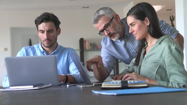 Young colleagues with older boss working with computers 