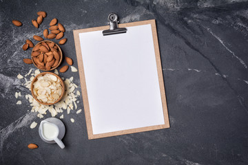 Top view of mock-up composition with clipboard and blank white sheet of paper with ingredients for almond milk