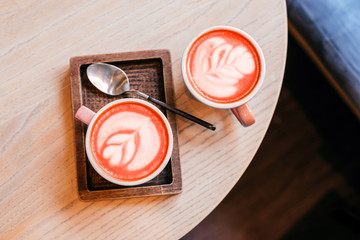 Two blue cups of cappuccino with beautiful latte art on the table on the wooden plate with spoon.
