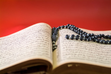 An open Koran with prayer beads on it