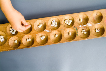 the hand of girl is playing Indonesian traditional mancala games