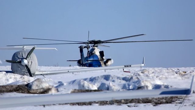 Civil transport helicopter launches engines before taking off from the snow ground of the airfield