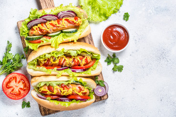 Hot dog with fresh vegetables on white top view.