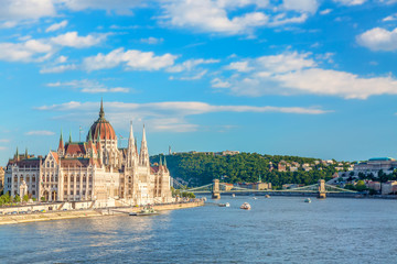 Fototapeta na wymiar Travel and european tourism concept. Parliament and riverside in Budapest Hungary with sightseeing ships during summer sunny day with blue sky and clouds