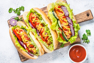 Hot dog with fresh vegetables on white top view.